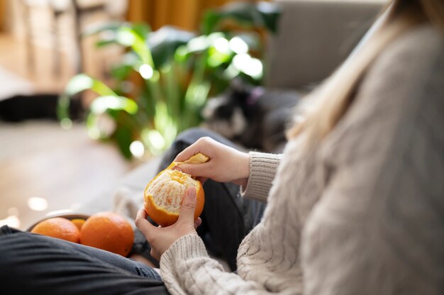 ソファでオレンジをはがしている若い女性