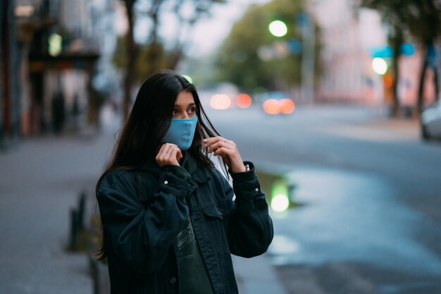 Young woman, person in protective medical sterile mask at empty street