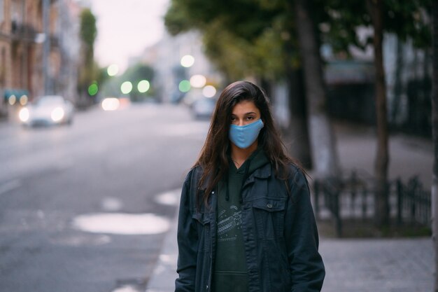 Молодая женщина, человек в защитной медицинской стерильной маске, стоящей на пустой улице,