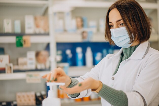 Young woman pharmacist desinfecting hands with sanitazer