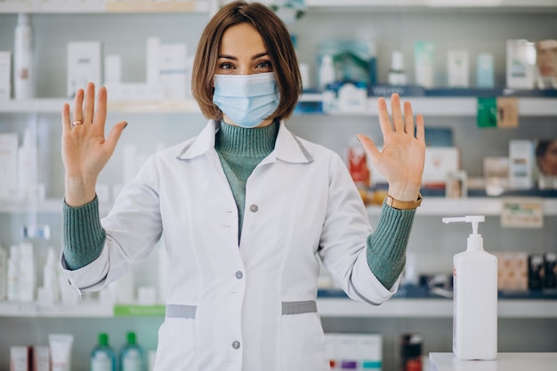 Young woman pharmacist desinfecting hands with sanitazer