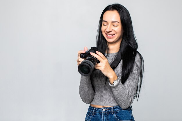 灰色の壁に分離されたカメラで撮影する若い女性写真家