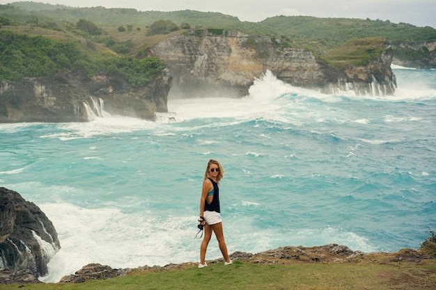 無料写真 崖の端にカメラを持つ若い女性写真家旅行者は自然の写真を撮ります