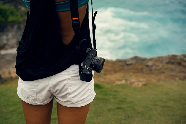 Молодая женщина-фотограф-путешественница с камерой на краю обрыва фотографирует природу