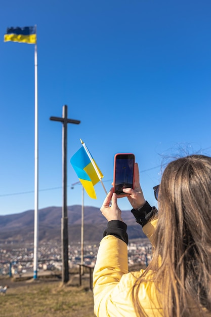 Una giovane donna fotografa la bandiera dell'ucraina sullo sfondo della città