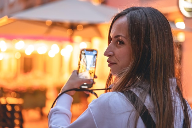 Молодая женщина фотографирует ночной город на смартфон