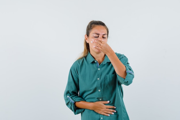 Foto gratuita giovane donna che pizzica il naso in camicia blu e sembra disgustata