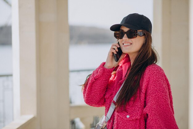 Giovane donna in cappotto rosa in piedi in strada