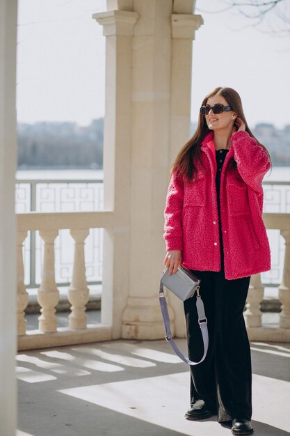 Young woman in pink coat standing in the street