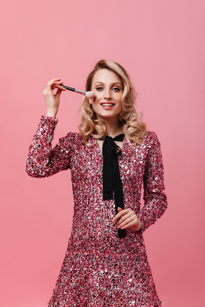 Young woman in pink dress holding fluffy makeup brush