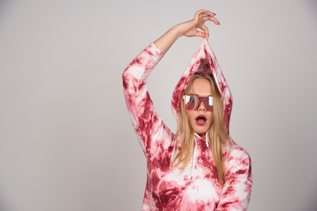 Young woman in pink glasses pulling her sweater.