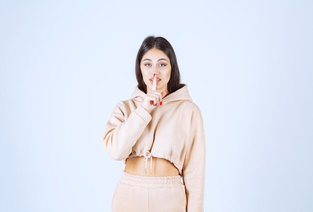 Young woman in a pink hoodie asking for silence