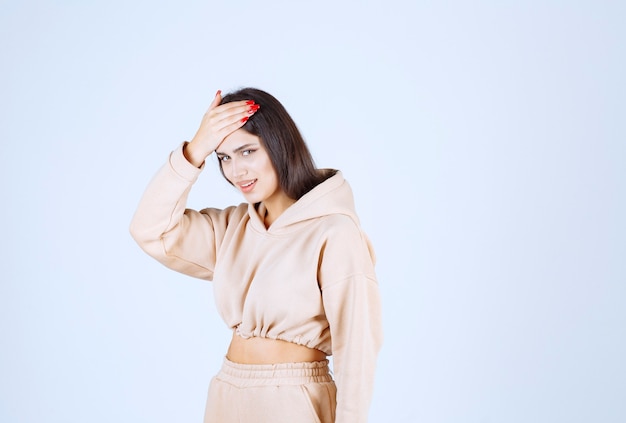 Young woman in a pink hoodie holding head as she has headache