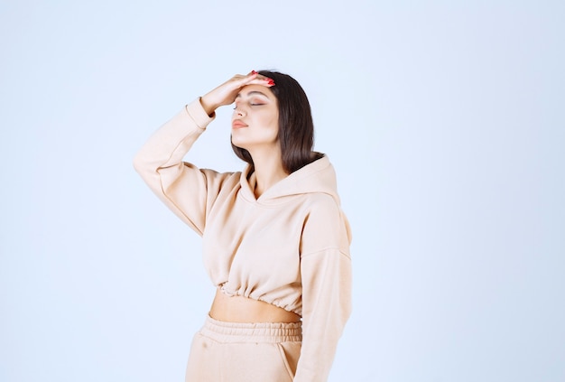 Free photo young woman in a pink hoodie holding head as she has headache