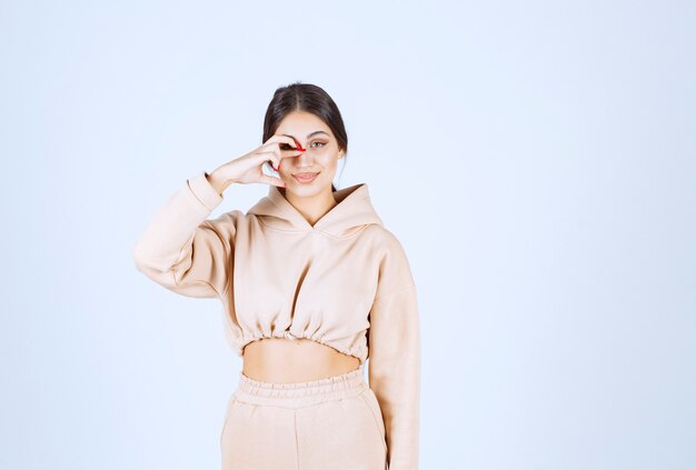 Young woman in pink hoodie looking through her fingers