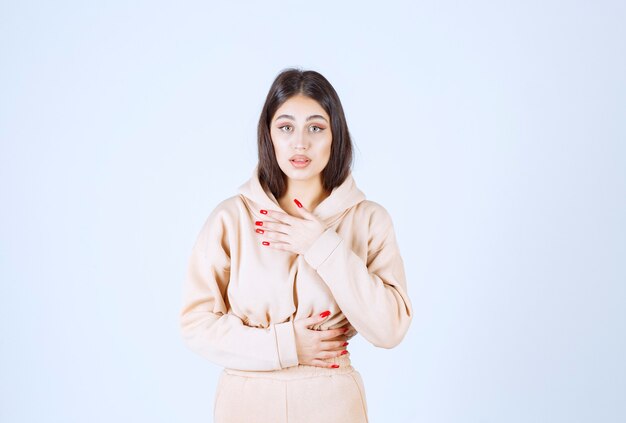 Young woman in a pink hoodie looks confused and thoughtful