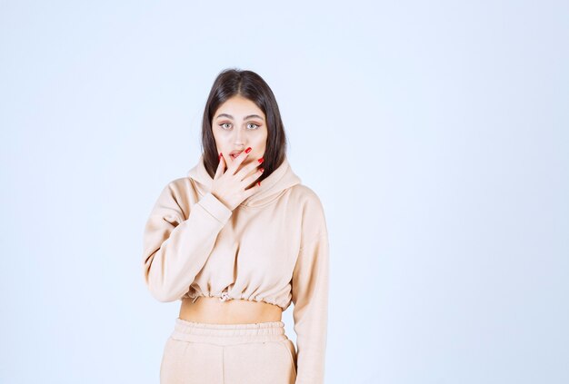 Young woman in a pink hoodie looks confused and thoughtful