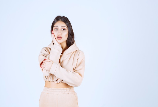 Young woman in a pink hoodie looks confused and thoughtful