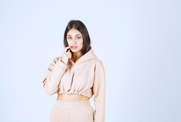 Young woman in a pink hoodie looks confused and thoughtful