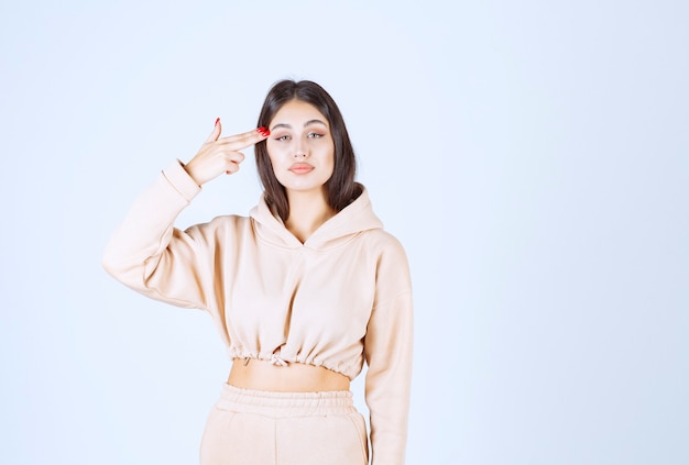 Young woman in a pink hoodie looks confused and thoughtful