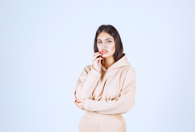 Young woman in a pink hoodie looks confused and thoughtful