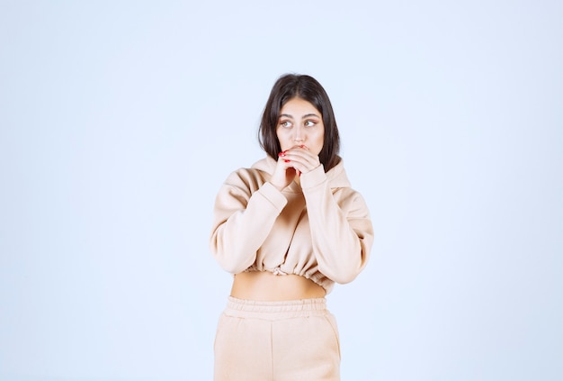 Young woman in a pink hoodie looks scared and terrified