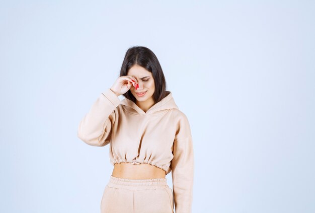 Young woman in a pink hoodie looks tired and sleepy