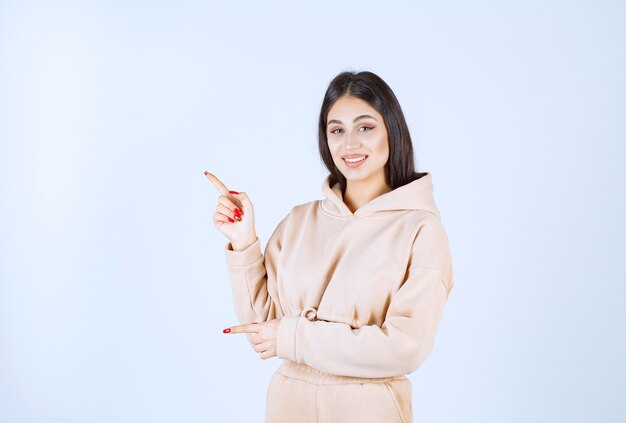 Young woman in a pink hoodie pointing to the left