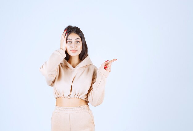 Young woman in a pink hoodie pointing to the right