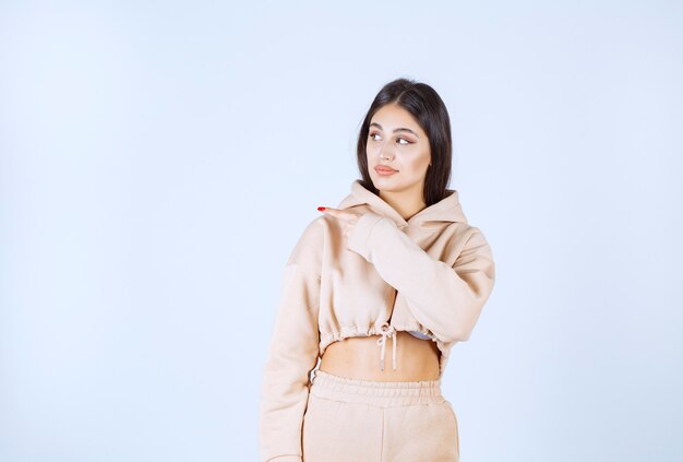 Young woman in a pink hoodie pointing something on the left