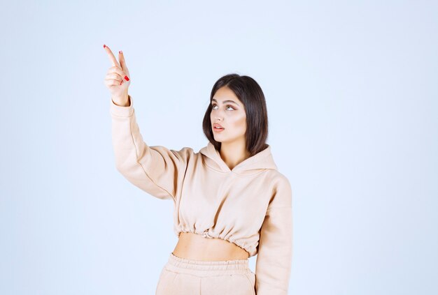 Young woman in a pink hoodie pointing somewhere above