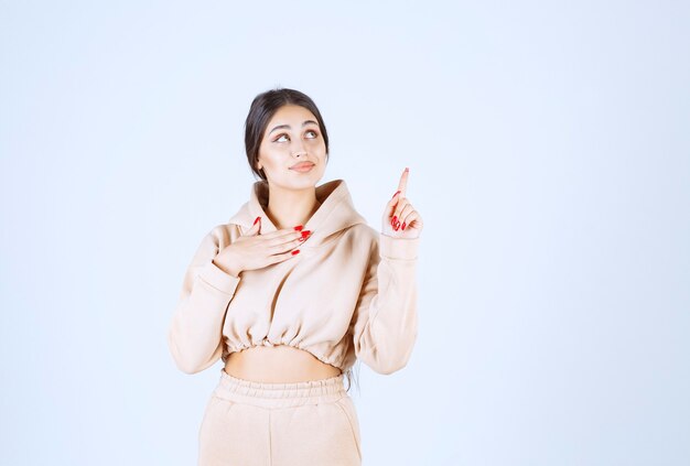 Young woman in a pink hoodie pointing somewhere above