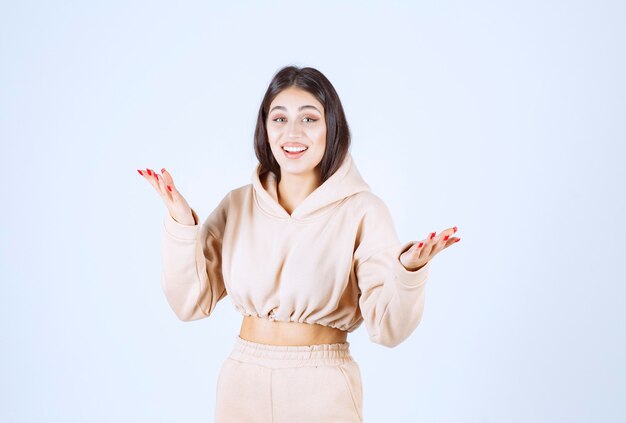 Young woman in a pink hoodie presenting something in her open hand