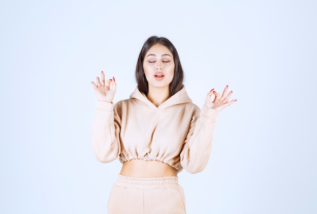 Young woman in a pink hoodie showing good hand sign