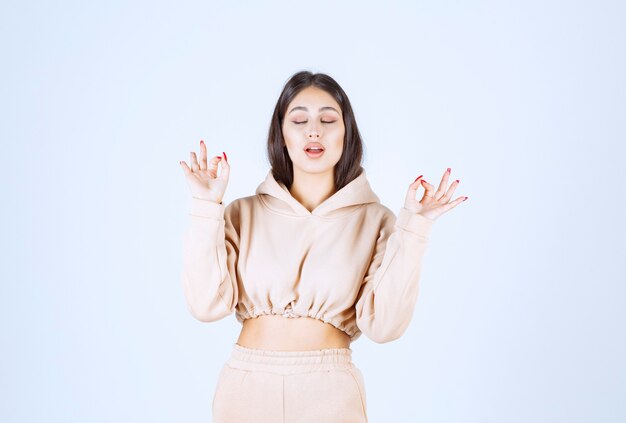 Young woman in a pink hoodie showing good hand sign