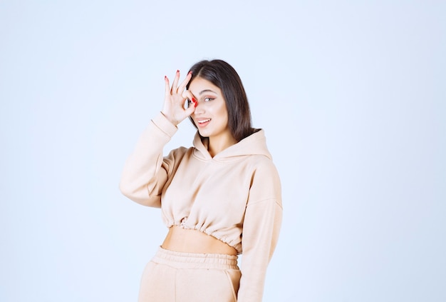 Young woman in a pink hoodie showing good hand sign