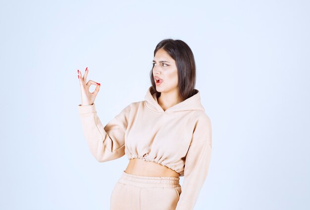 Young woman in a pink hoodie showing good hand sign