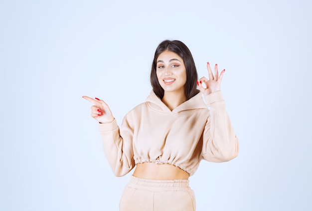 Young woman in a pink hoodie showing good hand sign