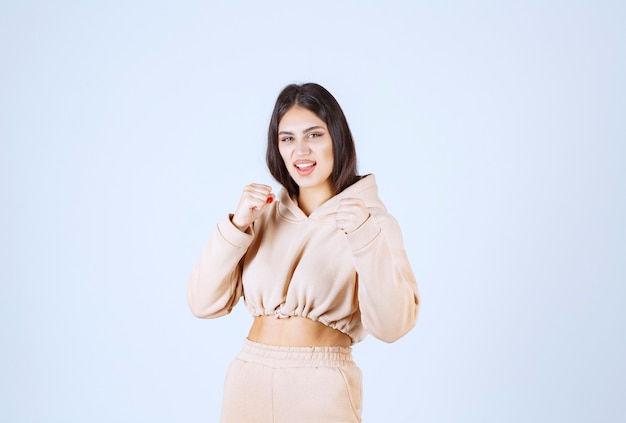 Young woman in a pink hoodie showing her muscles