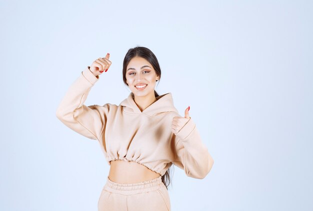 Young woman in a pink hoodie showing satisfaction hand sign