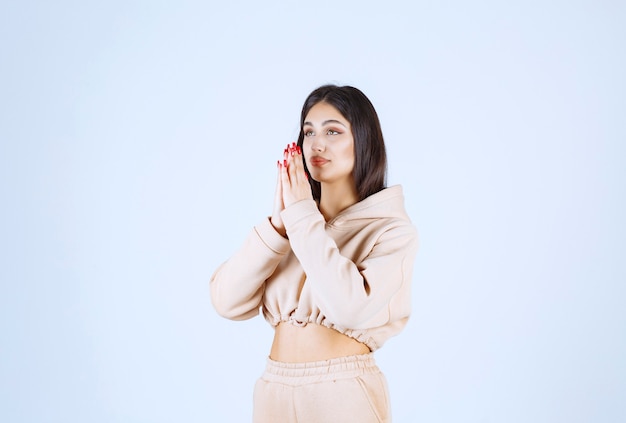 Young woman in a pink hoodie uniting hands and praying