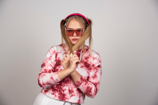 Young woman in pink outfit holding her ponytail hair.