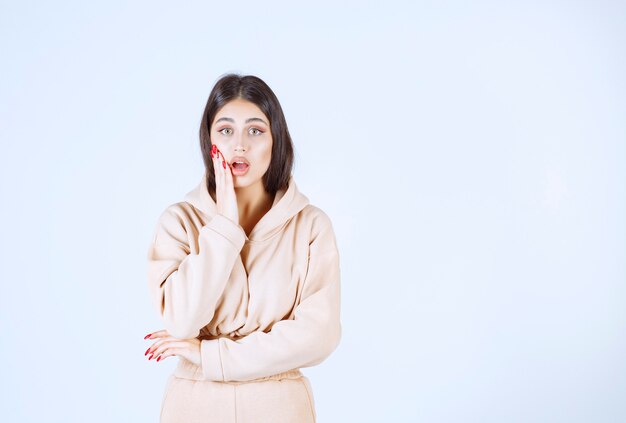 Young woman in pink pajamas looks surprized and terrified