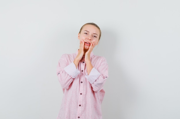 Young woman in pink shirt saying something with hands near mouth