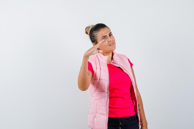 ピンクのTシャツとジャケットの若い女性がスケールを示して美しく見えるように手を伸ばして