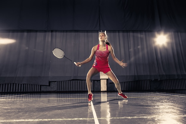 Young woman playing badminton over gym space