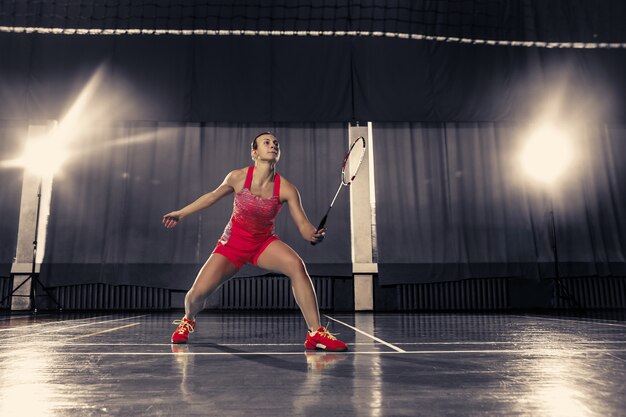 Young woman playing badminton at gym