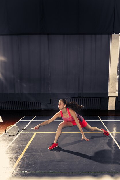 Young woman playing badminton at gym