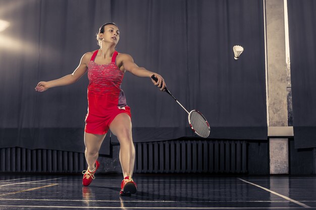 Young woman playing badminton at gym