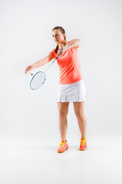 Young woman playing badminton over white wall